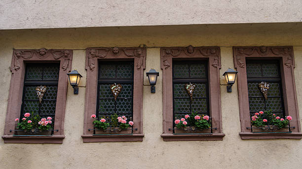 Decorative lanterns hanging on the windows of the traditional German food restaurant located in the half-timbered house in a historic city Aschaffenburg, Bavaria, Germany on August 30, 2025. Classic European street atmosphere and architectural detail. Fachwerk houses, German culture and construction traditions