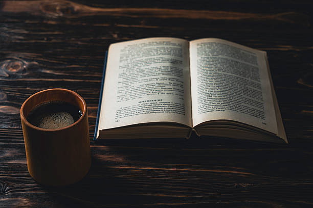 istock Open book and coffee cup on dark wooden table in warm light 2257942738