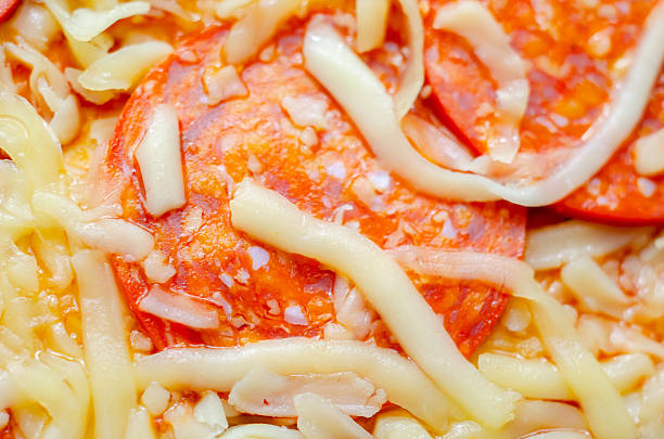 A slice of pepperoni pizza with cheese and onions. The onions are scattered around the pizza, adding a crunchy texture