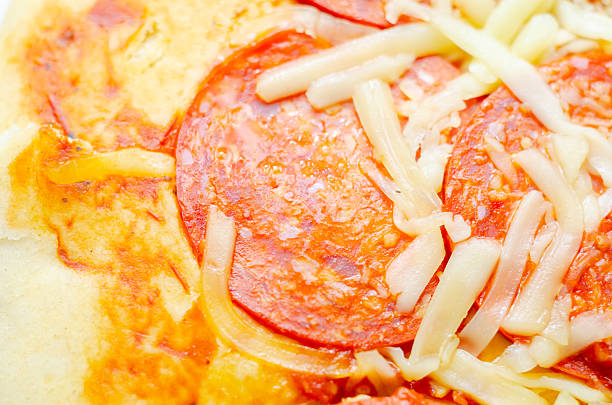 A slice of pepperoni pizza with cheese and onions. The onions are scattered around the pizza, adding a crunchy texture