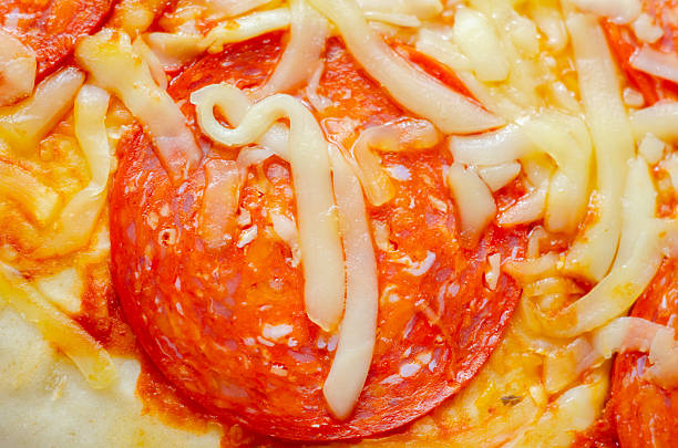 A slice of pepperoni pizza with cheese and onions. The onions are scattered around the pizza, adding a crunchy texture