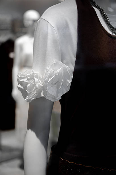 A mannequin dressed in a black sleeveless top with a white puffed sleeve shirt underneath, displayed in a store setting.