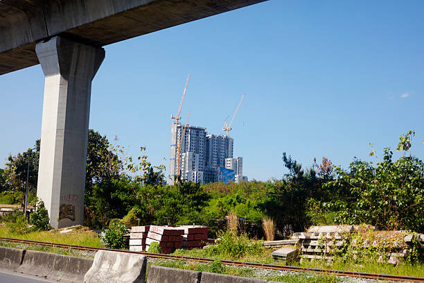 Construction site of skycraper behind Airport railway link seen from Kamphengphet Road under briudge of railway elevated train bridge in Bangkok near Makkasan
