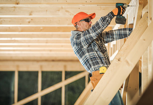A worker uses a drill to secure wooden beams at a construction site in the daylight hours.