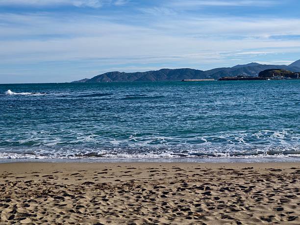 Tranquil Coastal Horizon With Gentle Surf And Clear Water, Soft Cloud Bands Above Distant Mountains, Calm Mood