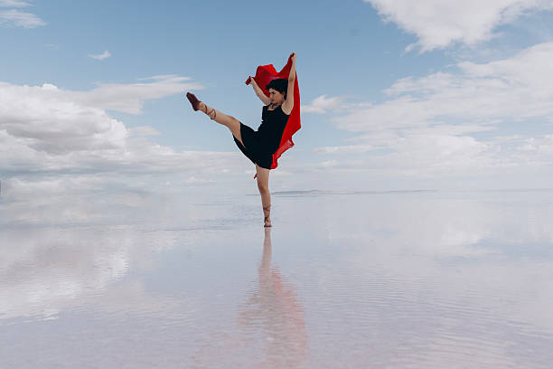 A modern young dancer dancing on the lake in red tulle.