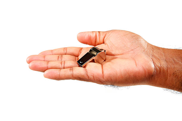 Shiny silver metal whistle resting gently in a person's open palm against a stark white background, emphasizing themes of judgment, refereeing, and giving clear instructions within sports or authority contexts.
