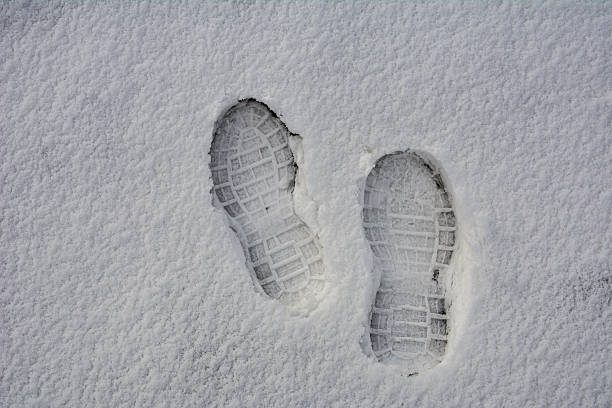 Clear deep footprints on white winter snow of a pair of boots. Track in snow. Overhead view. Texture of snow surface.foot prints in fresh snow