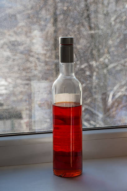 Red wine bottle and stylish wineglas.  Glasses of red wine standing on an old wooden table, warm sunset light penetrates through the window. The beautiful romantic atmosphere of the setting, calls for consummation. Shot with Canon 5DMarkIII, developed from RAW, Adobe RGB color profile. Shallow DOF for soft background.