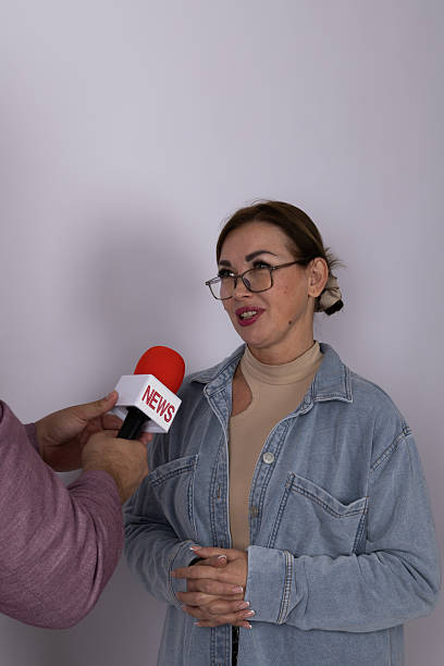 A journalist conducting an on-camera discussion in a studio setting.