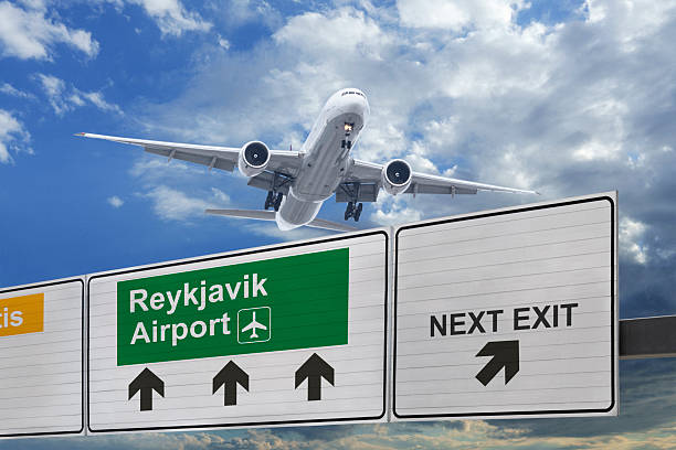 Airplane flying towards Reykjavik Airport sign under a cloudy sky
