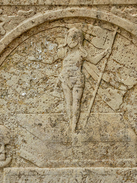 Weathered limestone relief showing a medieval knight with shield and spear beneath an arched frame. The worn surface adds timeless character, evoking heritage and ancient crafts. Ideal for topics on sculpture, history, Denmark, medieval symbolism, and cultural monuments.