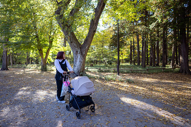 Mother with a baby in stroller walking in forest