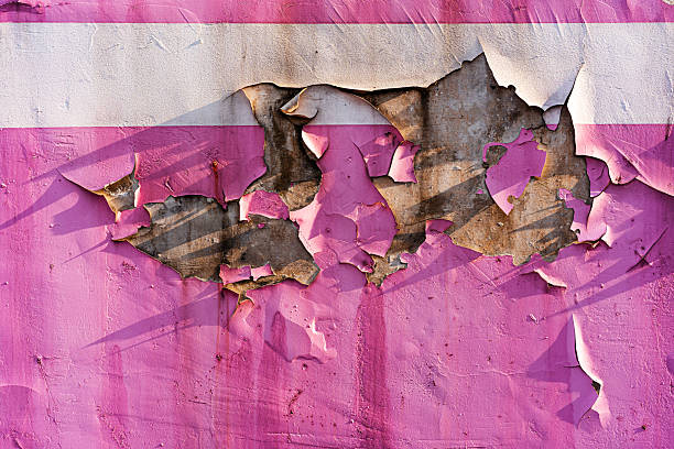 Cracked pink paint peeling from the wall