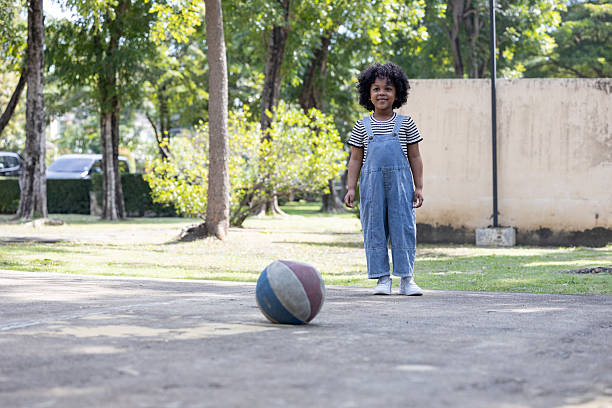 Little adorable toddler girl playing with ball outdoors. Happy smiling child catching and throwing, laughing and making sports. Active leisure with children and kids