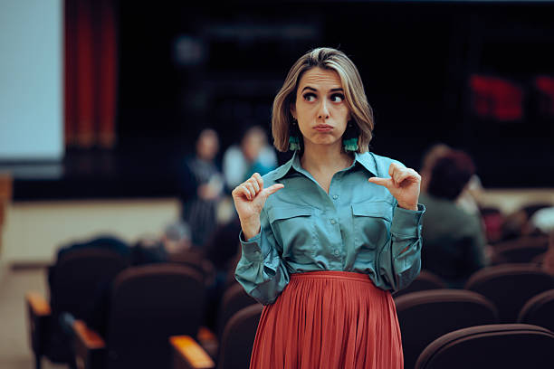 female actress alone on stage sitting barefoot on a chair and glancing
