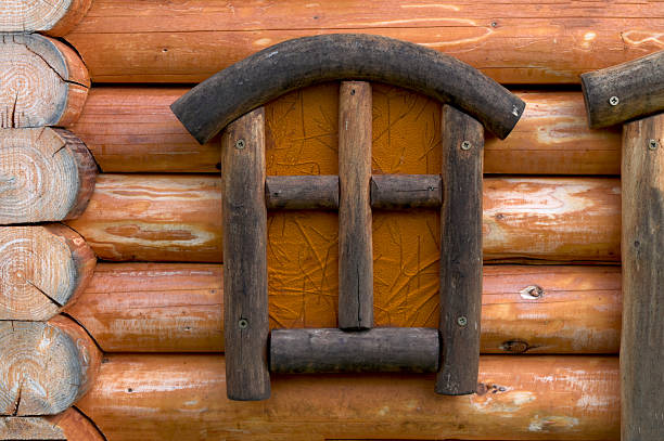 Old wooden window frame on a log house wall. Traditional rural architecture, natural wood texture, rustic and ethnic style background for design concepts.