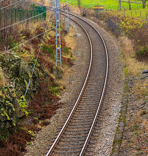 Curved railway track running through rural landscape with rocks and green fields