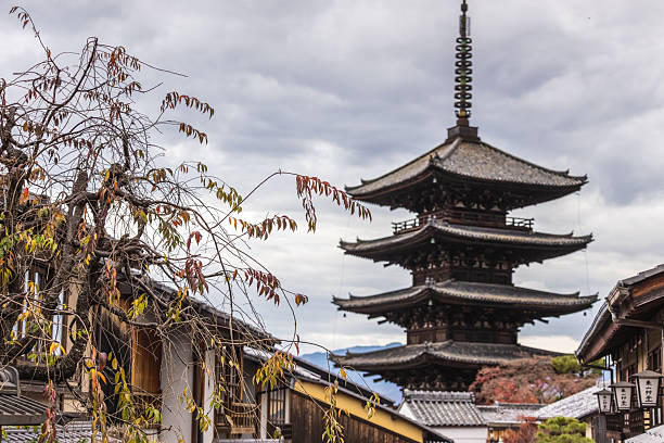 Kyoto, Japan - December 06, 2025: Majestic Yasaka Pagoda (Hokan-ji Temple) in Kyoto's historic Higashiyama district, framed by traditional Japanese architecture and autumn foliage under a cloudy