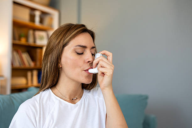 istock Young woman using a pressurized metered-dose asthma inhaler to treat respiratory issues or allergic reaction at home sitting on sofa managing asthma attack or chronic bronchitis symptoms 2258075576