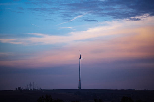 A single wind turbine standing against a colorful evening sky, representing renewable energy, sustainability, clean power, and environmental technology.