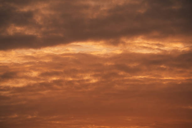 Close-up view of an intense sunset sky filled with glowing orange and red clouds. The dramatic natural light and cloud formations create an abstract atmospheric background suitable for themes of nature, weather, and climate.