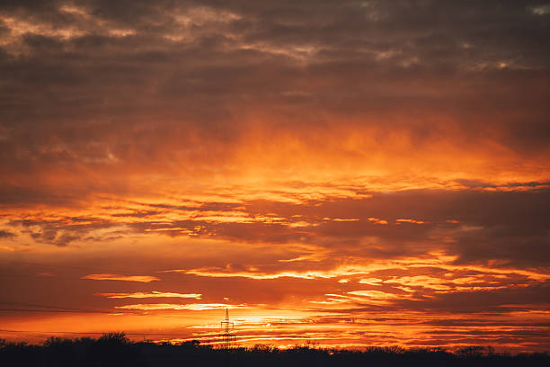 Close-up view of an intense sunset sky filled with glowing orange and red clouds. The dramatic natural light and cloud formations create an abstract atmospheric background suitable for themes of nature, weather, and climate.