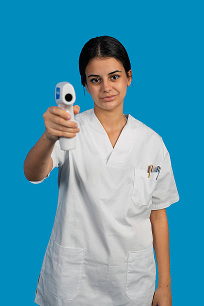 Young adult female healthcare worker holding a non-contact thermometer for health screening