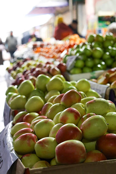 Stems of large sunflowers and baskets of green chile peppers displayed at a weekly Cape Cod farmers' market