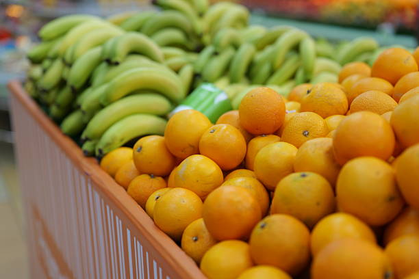 Close view of fresh oranges and bananas arranged in a grocery produce section, emphasizing natural color and healthy food choices.