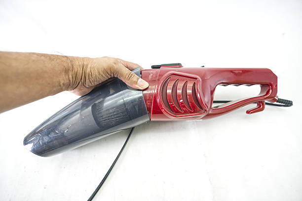 A close-up of a woman using a vertical wireless vacuum cleaner to clean the floor.