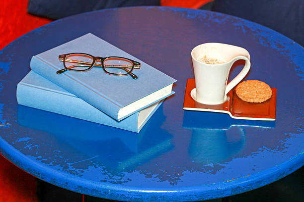 Books With Reading Glasses and Coffee Cup Cookie at Tray Blue Table