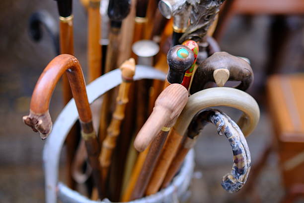 Assorted vintage walking canes with carved and decorative handles displayed in a container at a flea market. The image highlights craftsmanship, traditional design, and second-hand objects, evoking heritage, aging, and classic accessories. No people visible.
