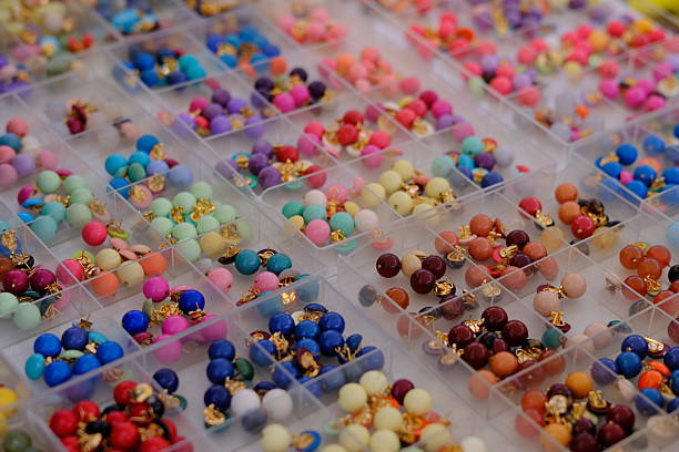 Colorful beaded earrings arranged in small transparent display boxes. The repetition of shapes and vibrant pastel tones creates a playful pattern highlighting handmade jewelry, craftsmanship, fashion accessories, and creative design. No people visible.