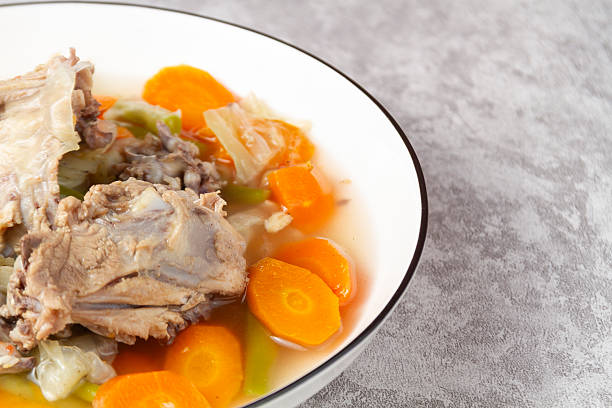 Close up of chicken stock being boiled with bones and carrots and vegetables home made