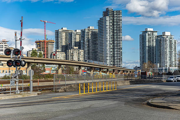 New residential areas with modern architecture apartment building complex and railway line in front. Elevated rail road of urban public transit system. Vancouver SkyTrain Canada Line to Richmond BC
