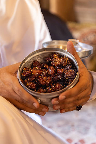 Arab man offering dates to guests at Iftar ramadan celebration for traditional welcome