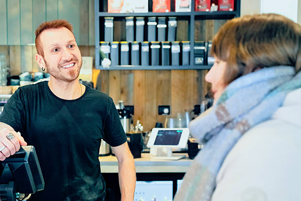 Smiling barista speaking with customer in  cafe.