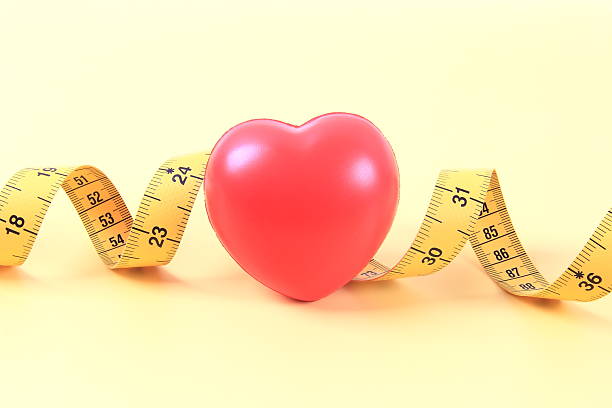 Red heart and tape measure on yellow background