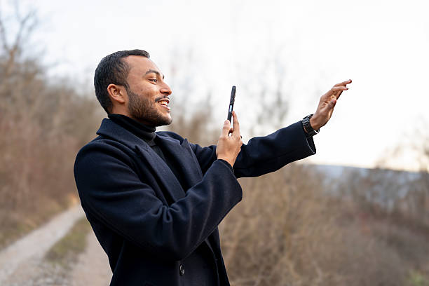 Young adult man smiling while having a video call on his smartphone outdoors