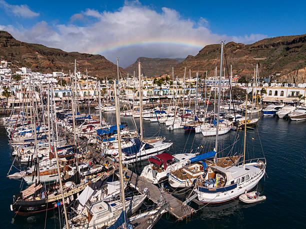 Colorful rainbow appears in the sky over the small harbour and picturesque fishing village of Mogan, Gran Canaria, Canary Islands, Atlantic Ocean, Spain