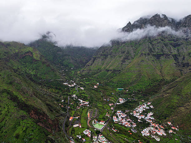 Traditional village of houses scattered along a green valley and among high mountains in the fog, Agaete municipality, Gran Canaria, Canary Islands, Atlantic Ocean, Spain