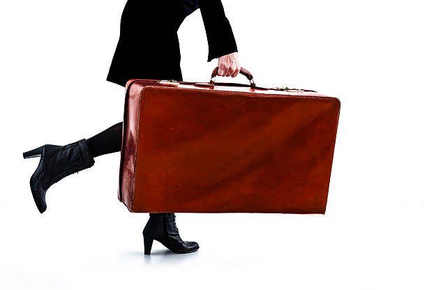 Heavy antique suitcase carried by someone against white background