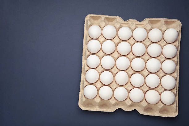 White chicken eggs in the cardboard egg tray with rooms for twenty eggs isolated on white background, with clipping path included