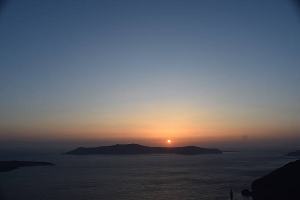 A view from Fira, Santorini as the sun sets over one of the nearby islands.