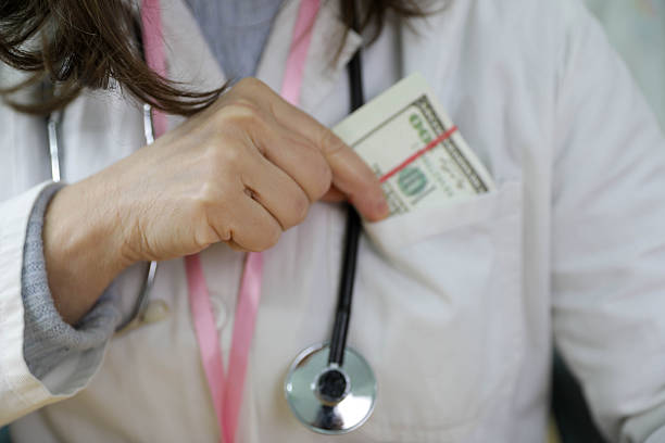 Female Doctor Hiding Cash Money In Medical Coat Pocket While Wearing Stethoscope, Illustrating Healthcare Bribery, Illegal Payments, Ethical Violations, Corruption In Medical System And Abuse Of Professional Trust.