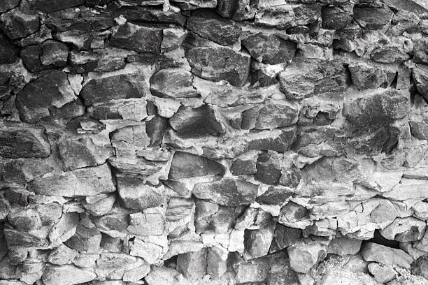 Rustic rubble masonry wall with irregular, rough-hewn stones of various sizes, bound by visible mortar, creating a textured, aged surface.