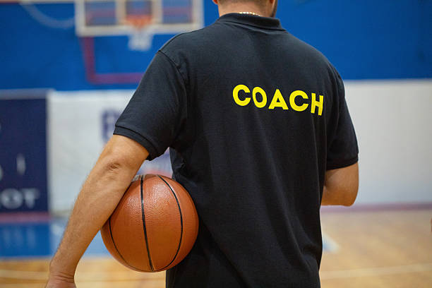 Basketball coach holding a ball on the court during training, ready to give instructions to his team