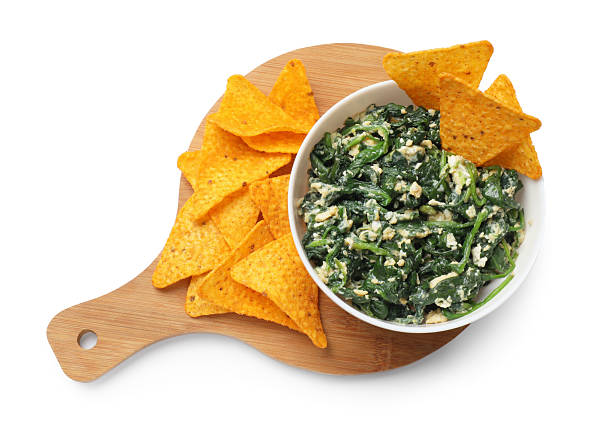 Tasty spinach dip with eggs in bowl and nachos chips isolated on white, top view
