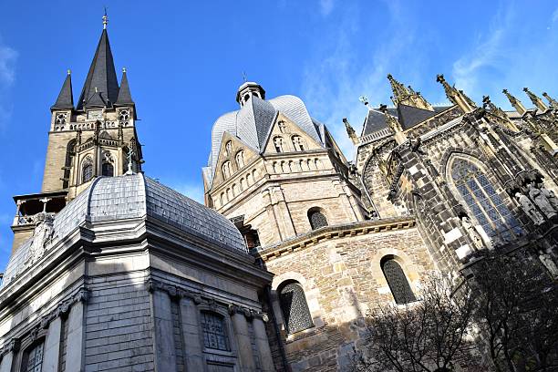 A close-up view of the intricate gothic architecture at the side of the Aachen Cathedral, showcasing the fine details of the stonework and statues.